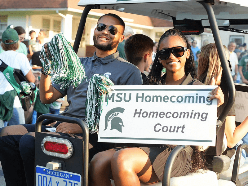 Two students on golf cart at homecoming parade