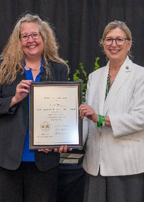 Angela Wilson poses with MSU Interim President Teresa Woodruff with her Beal Outstanding Faculty Award plaque.